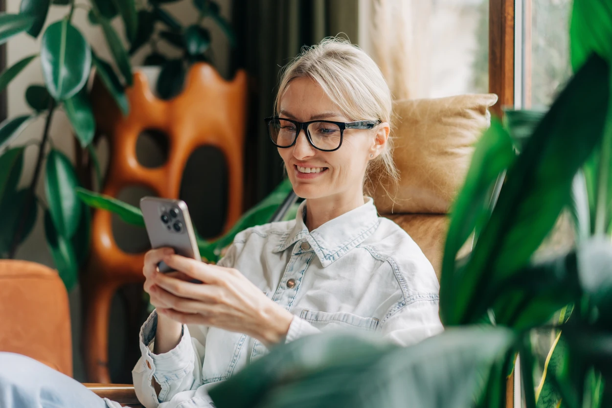 Smiling woman in glasses holding her phone