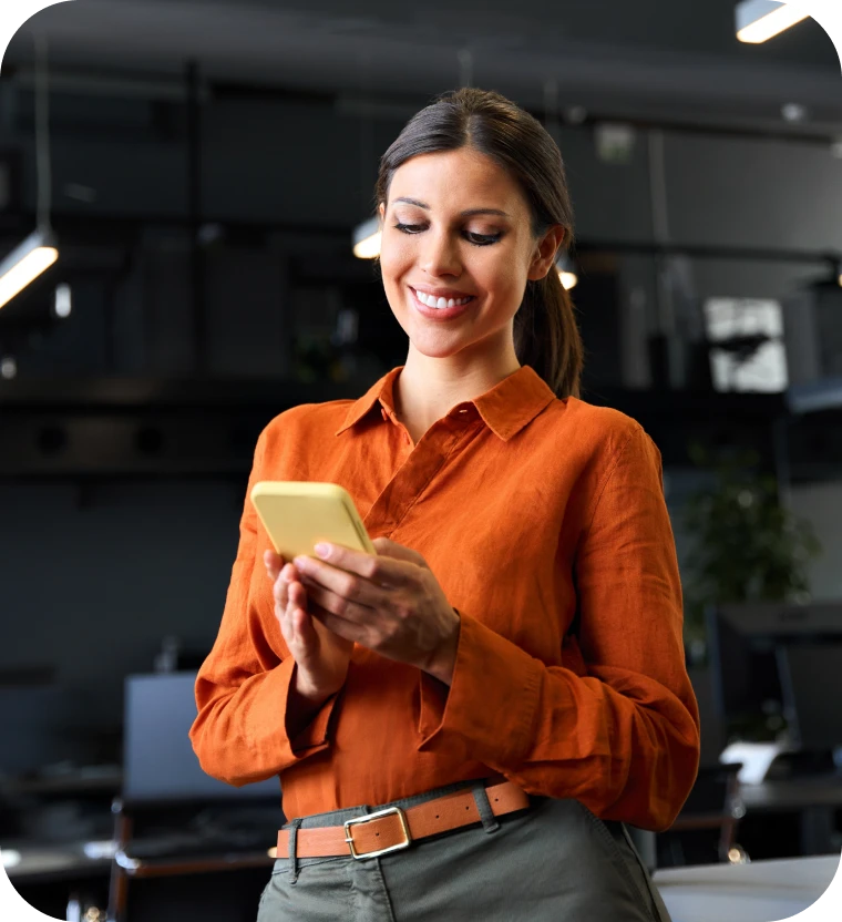 Smiling woman in an orange shirt reading her phone